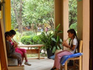 three girls practice on their flutes on the school's porch