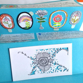 Hand written letter on white pieces of paper glued over rich blue paper, it has a row of hand painted whimsical flower stickers and a paper cut out in progress